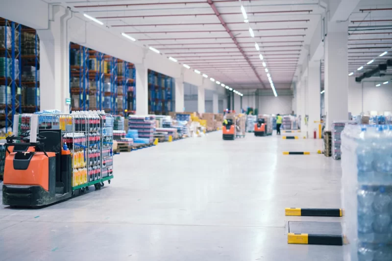 Warehouse industrial building interior with people and forklifts handling goods in storage area Free Photo