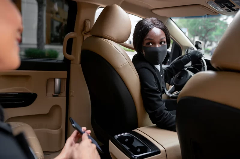 Woman driving her taxi cab with her client on the backseat Free Photo