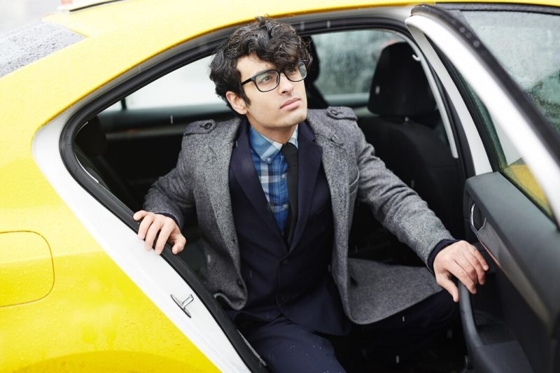 Young entrepreneur leaving taxi in rain Free Photo