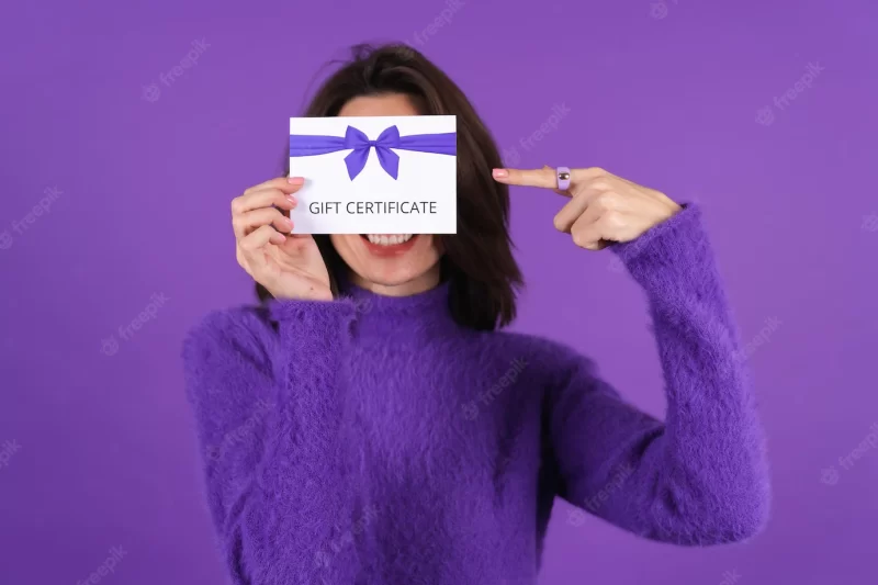 Young woman in purple soft cozy sweater with gift voucher Free Photo
