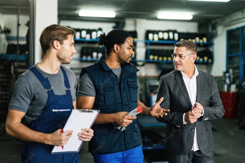 African american auto mechanic and his coworker communicating with their manager in repair shop Free Photo