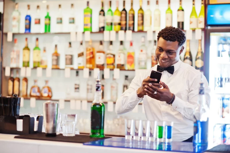 African american bartender at bar making coctails on shots and shoot photo on phone alcoholic beverage preparation Free Photo