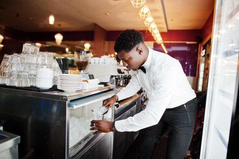 African american bartender at bar picks up ice alcoholic beverage preparationFree Photo