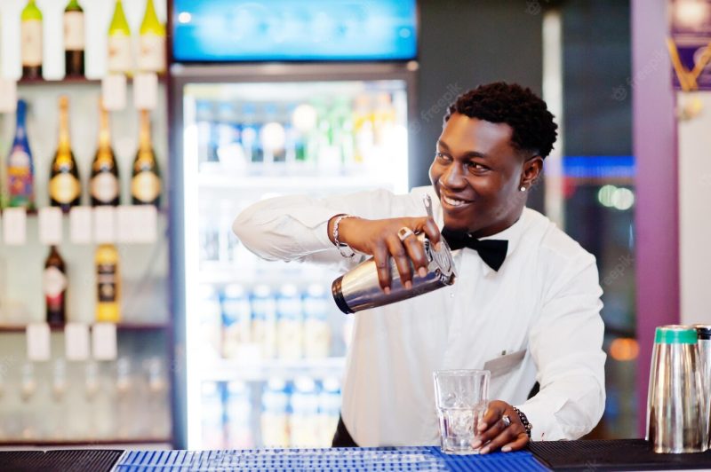 African american bartender at bar with shaker alcoholic beverage preparation Free Photo