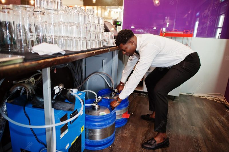 African american bartender at bar with stainless steel beer barrel Free Photo