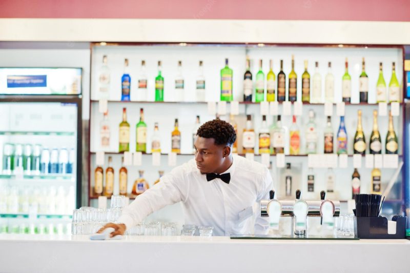 African american bartender wearing bow tie cleaning bar Free Photo