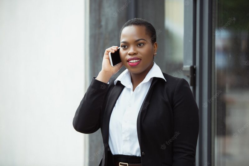 African American businesswoman in office attire smiling, looks confident and happy, busy Free Photo