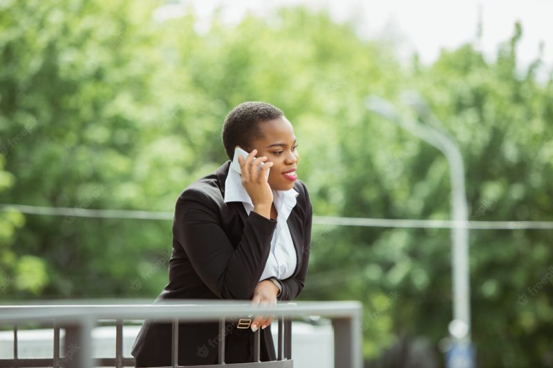 African American businesswoman in office attire smiling, looks confident and happy, busy Free Photo