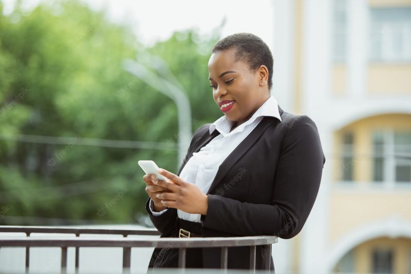 African American businesswoman in office attire smiling, looks confident and happy, busy Free Photo