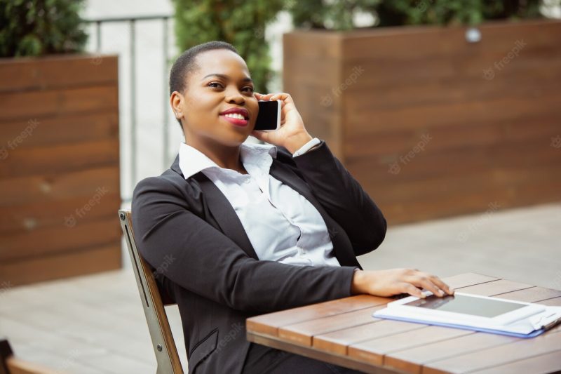 African American businesswoman in office attire smiling, looks confident and happy, busy Free Photo