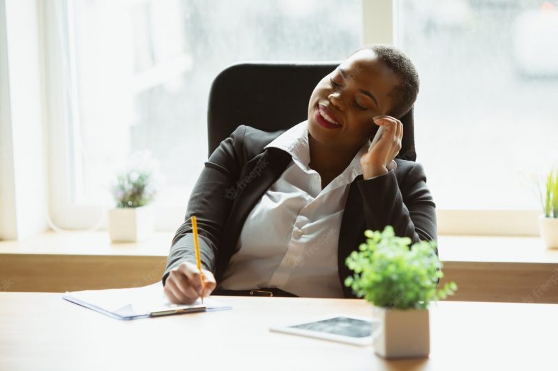 African American businesswoman in office attire smiling, looks confident and happy, busy Free Photo