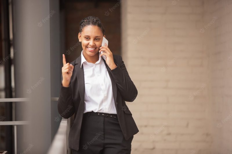 African-american businesswoman in office attire smiling, looks confident and happy, successful Free Photo