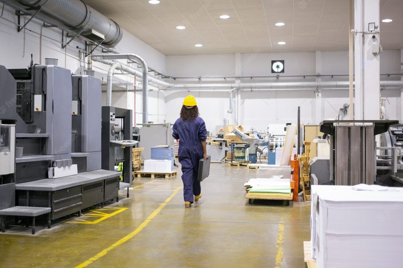 African american female industrial employee in hardhat and overall walking on plant floor Free Photo