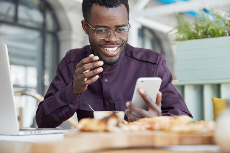 African American male in formal clothes, shares multimedia files in message, types feedback, organize schedule Free Photo