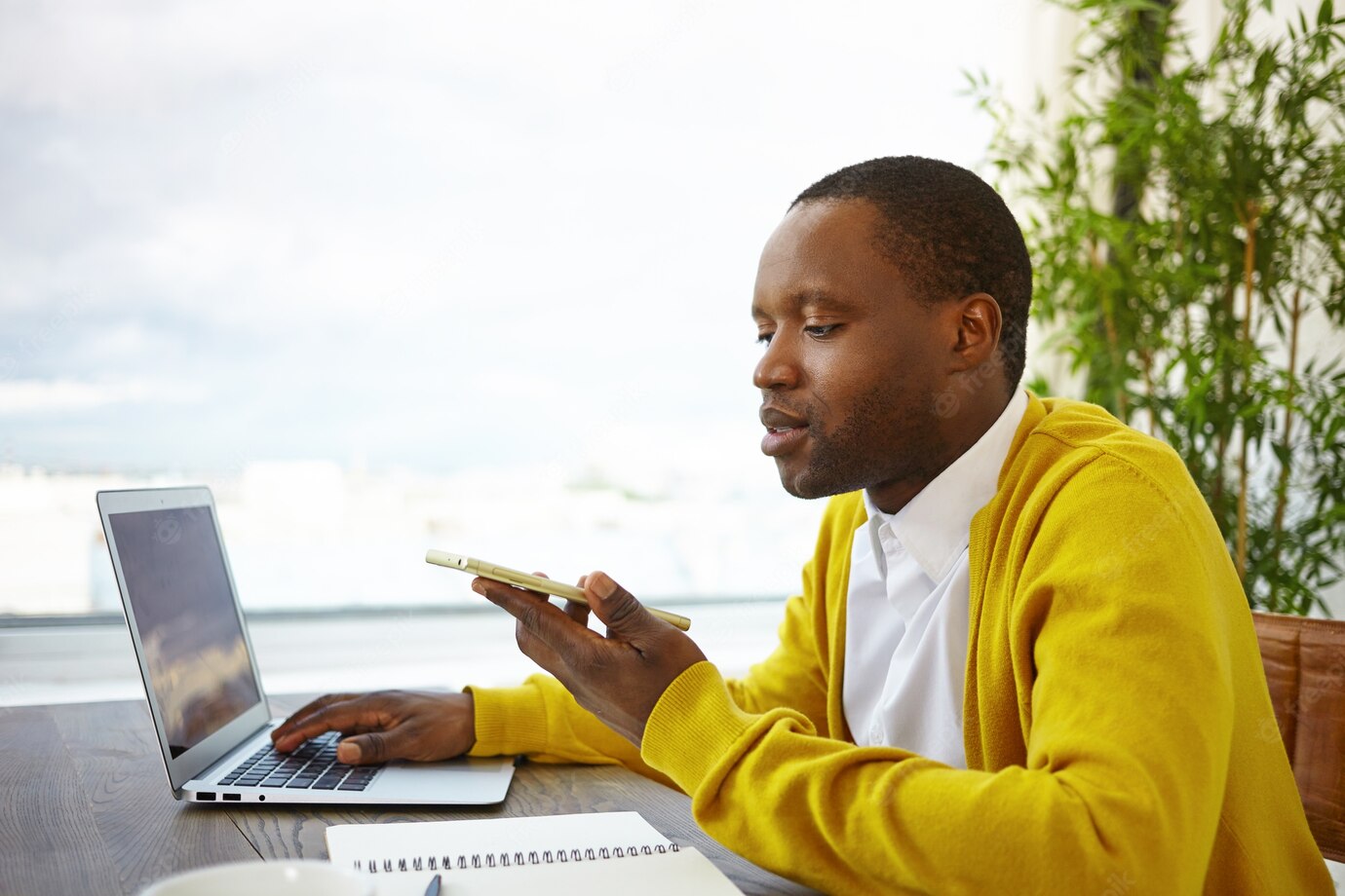 African American Male Freelancer Sitting By Large Window Hotel Lobby Using Wireless Internet Connection Working Remotely Laptop Sending Voice Message Via Online App Mobile Phone 343059 756