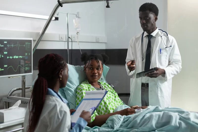 African american man and woman talking to girl in hospital ward about healing treatment and diagnosis. doctors examining sick young patient with cervical neck collar sitting in bed Free Photo