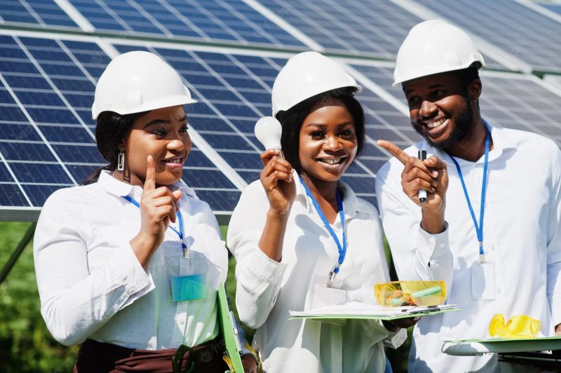 African american technician checks the maintenance of the solar panels group of three black engineers meeting at solar station hold led bulb Free Photo