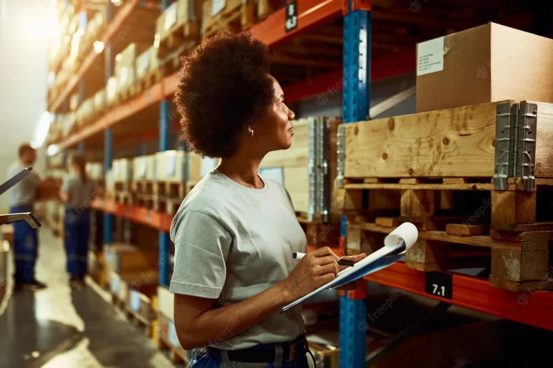 African american worker writing inventory list while checking stock in storage room Free Photo