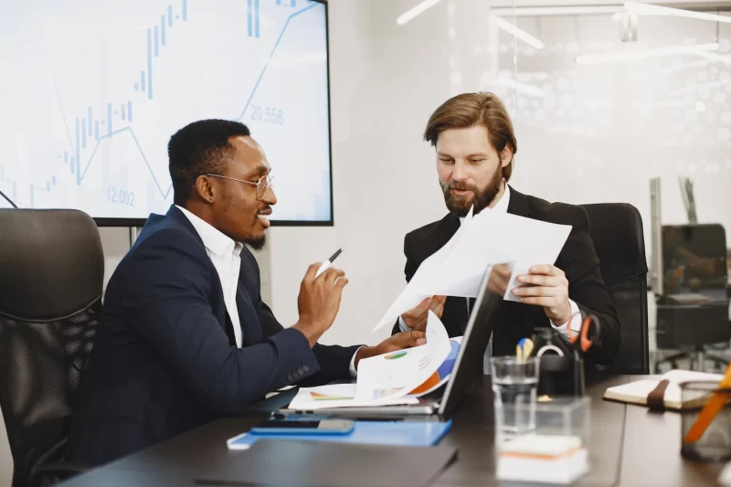 African man in a black suit. international partners. people sitting at the table with laptop. Free Photo