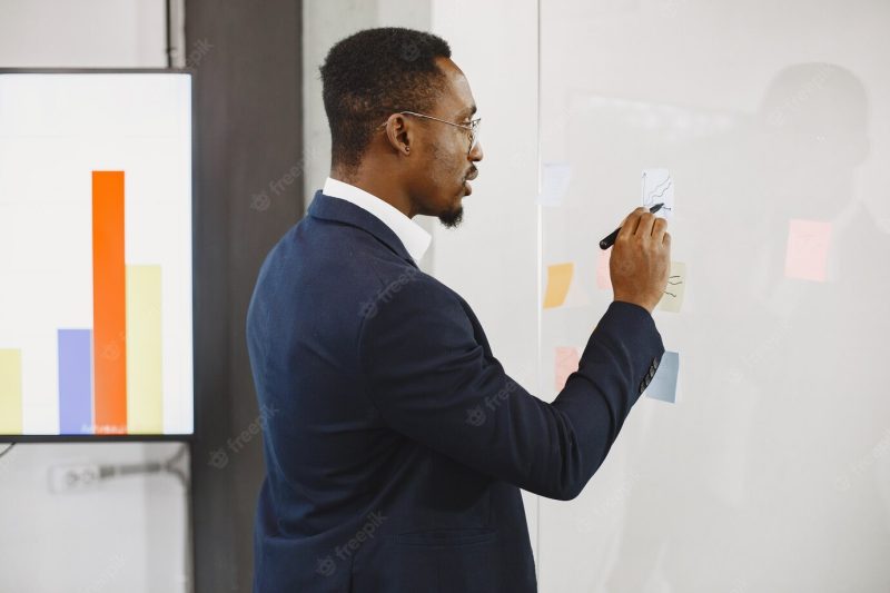 African man in a black suit. man writing on the glass. Free Photo