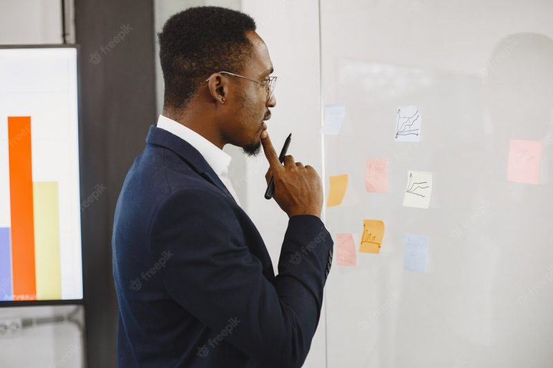 African man in a black suit. man writing on the glass. Free Photo