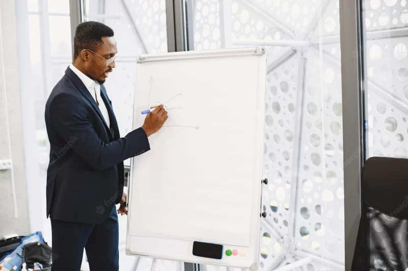 African man in a black suit. writing board. guy do presentation. Free Photo