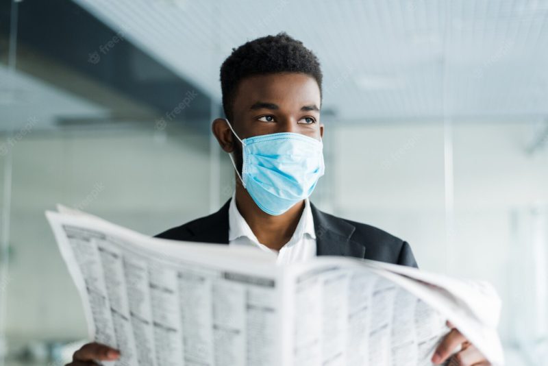 African man read last newspapers wearing in mask about situation in world in office Free Photo