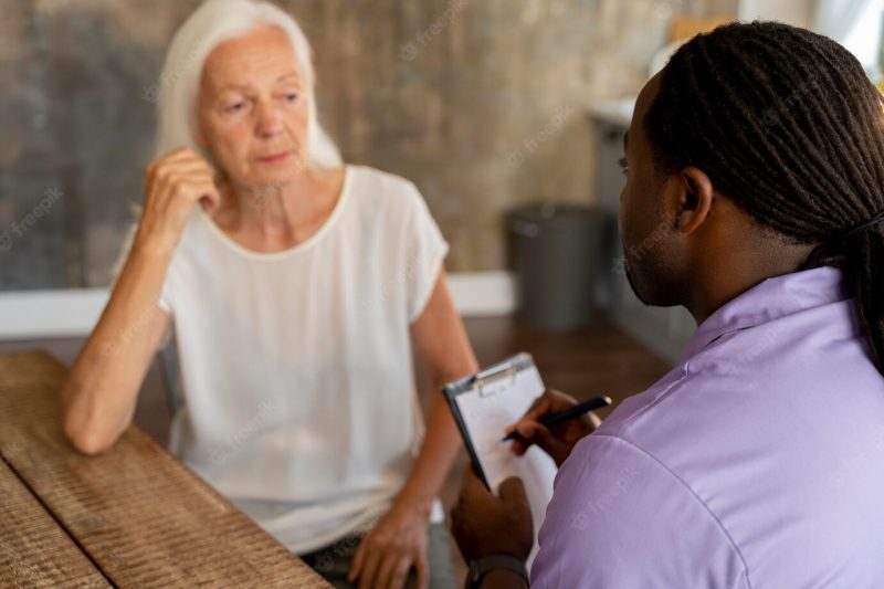 African social worker helping a senior woman Free Photo