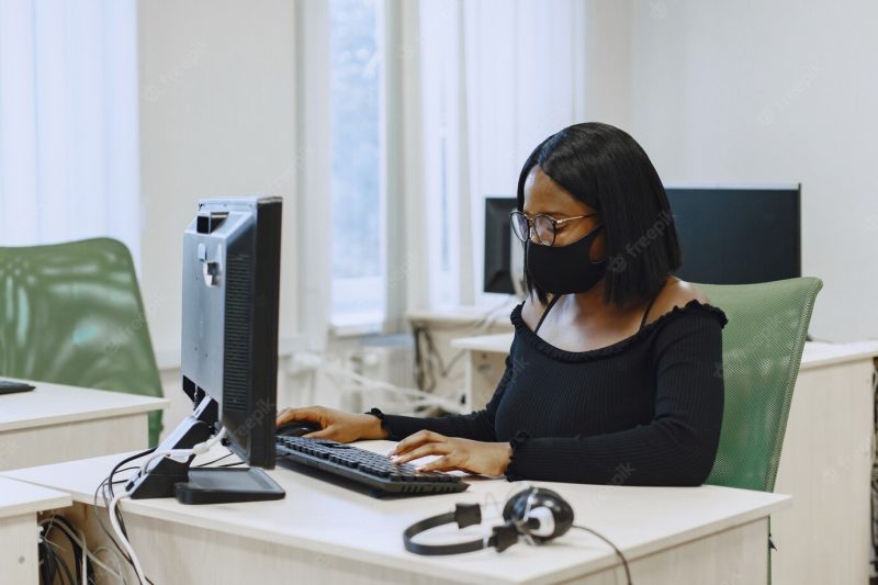 African woman sitting in computer science class. lady with glasses. female student sitting at the computer. Free Photo