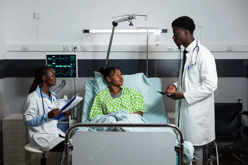 Afro doctors consulting young adult in hospital ward Free Photo