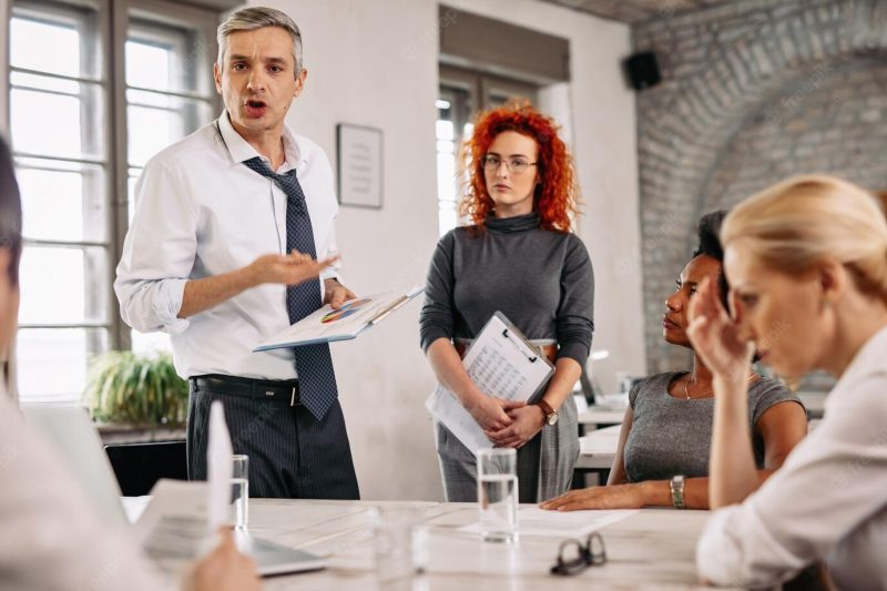 Angry businessman feeling disappointed with business reports and scolding his team during a meeting in the office Free Photo