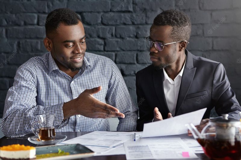 Attractive African businessman in glasses and suit holding papers Free Photo