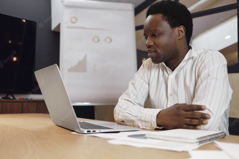 Attractive serious African American businessman in striped shirt working Free Photo