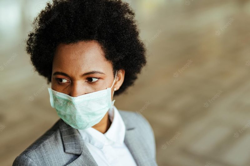 Black businesswoman wearing protective mask on her face while being at public corridor Free Photo