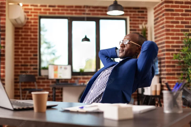 Business man relaxing after finishing task, taking break in startup office. employee feeling carefree, sitting with hands over head to relax and daydream after job is done. peaceful adult Free Photo