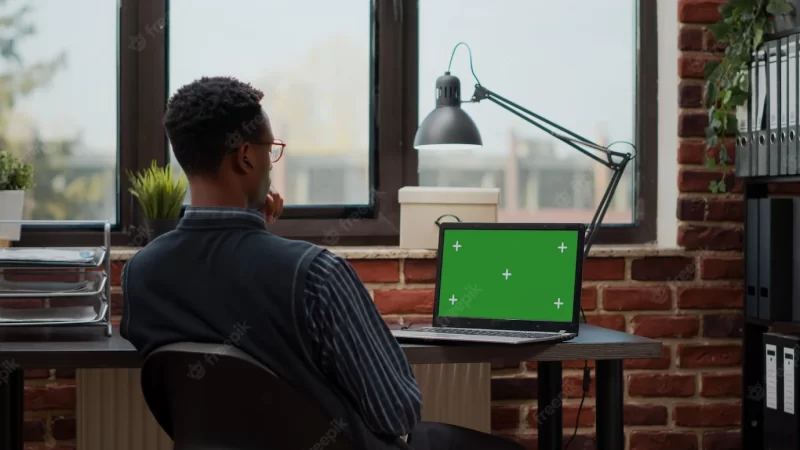 Business man working with laptop and green screen on display, using chroma key template with mock up background and isolated copy space. company employee with blank screen in office. Free Photo