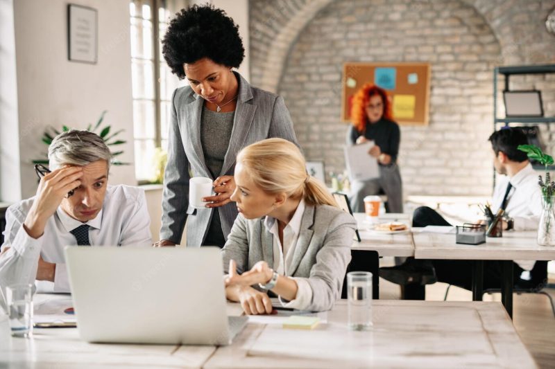 Business team having problems and talking while using laptop in the office focus is on African American business woman Free Photo