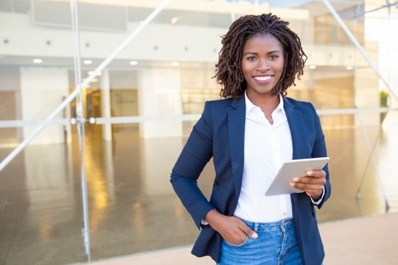 Businesswoman holding tablet pc and smiling at camera Free Photo