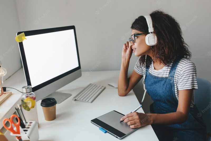 Busy cute girl in vintage outfit using tablet for work spending time in office Free Photo