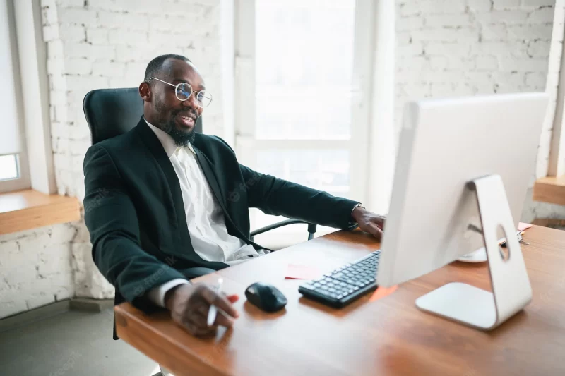 Calling, talking on phone. african-american entrepreneur, businessman working concentrated in office. looks serios, busy, wearing classic suit. concept of work, finance, business, success, leadership. Free Photo