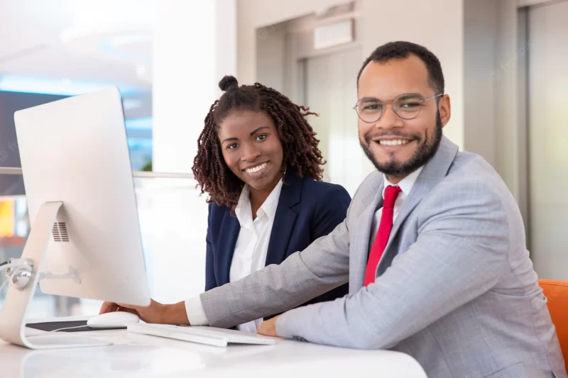 Cheerful business people using desktop computer Free Photo