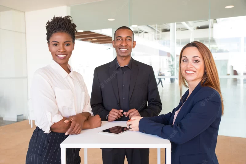 Cheerful successful team of three posing in office hallway Free Photo