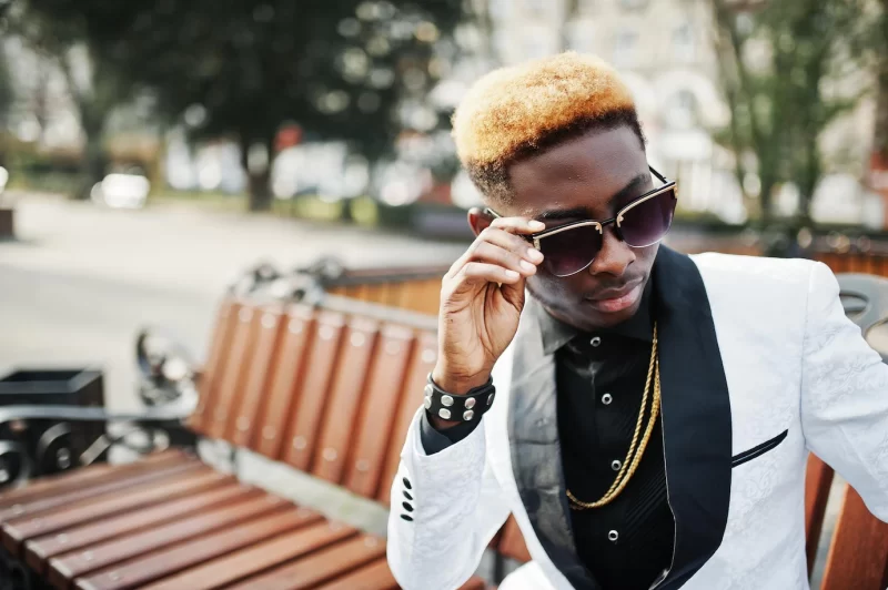 Chic handsome african american man in white suit and sunglasses sitting on bench Free Photo