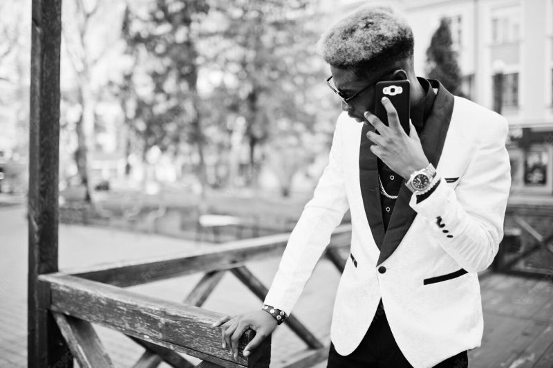 Chic handsome african american man in white suit with mobile phone at hand Free Photo