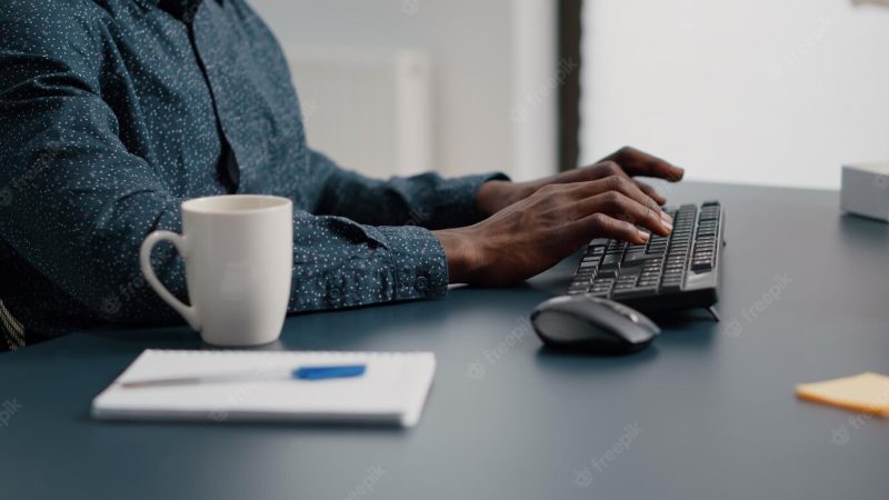 Close up of african american man hands typing on computer keyboard in living room, using internet online web communication from home office. remote worker working from home Free Photo