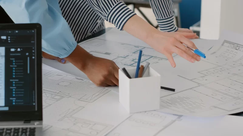 Close up of architects doing teamwork to design blueprints plans for building model on table. team of women working with industrial sketch and layout print plan. architectural project Free Photo