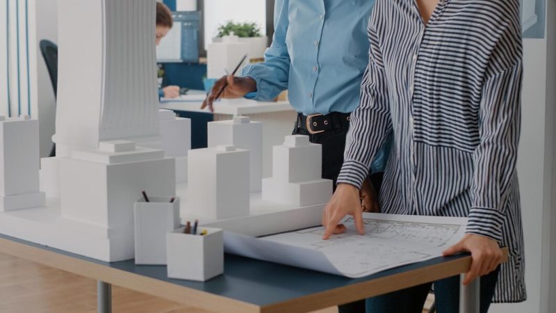 Close up of diverse team of women working on blueprints design in office. multi ethnic architects using industrial print on table to plan construction layout for architecture project. Free Photo