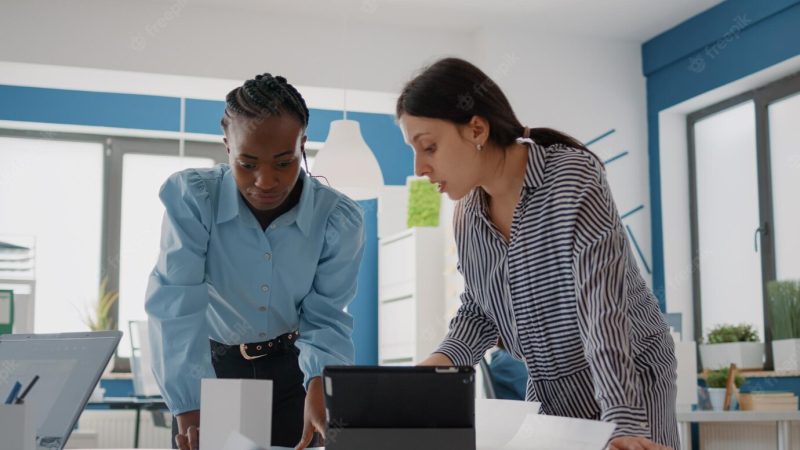 Close up of multi ethnic people working with blueprints plan to design architectural building. women using digital tablet and planning construction layout with sketch, brainstorming ideas. Free Photo