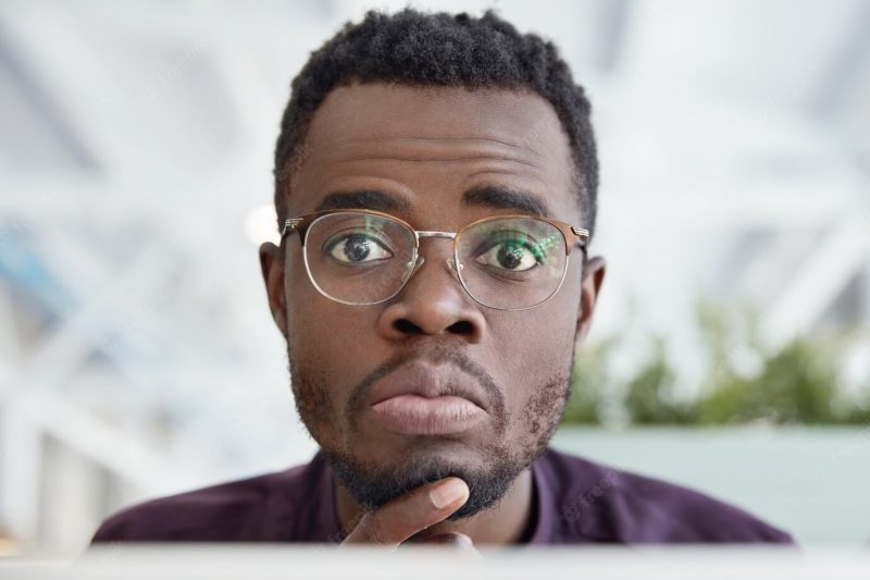 Close up shot of handsome African American male with dark pure skin, wears round spectacles and formal clothes Free Photo