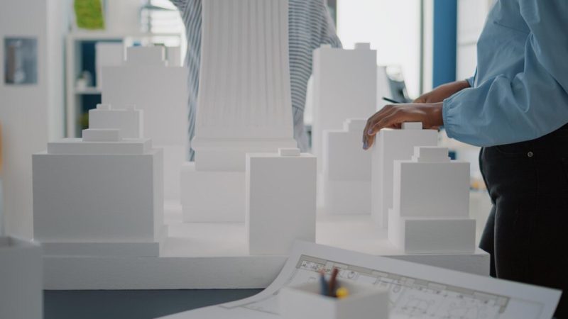 Close up of women with building model and blueprints plan on table. diverse architects working with maquette and industrial sketch to design construction structure and strategy project. Free Photo